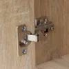 A close-up of a cabinet hinge attached to wooden surfaces. Produktbild-Vorschau