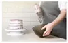 A person is using a hand mixer to prepare cake frosting next to a partially decorated cake. Anteprima dell’immagine prodotto