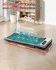 A compact treadmill is shown on a wooden floor in a room with furniture in the background. Produktbild-Vorschau