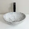 A marble-patterned sink with a black faucet is shown on a white countertop. Náhľad obrázku produktu