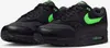 A pair of black Nike Air Max 1 Essential sneakers with green accents. Produktbild-Vorschau