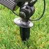 A close-up view of a black solar ground spotlight stake inserted into green grass. Produktbild-Vorschau