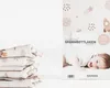 A product package for a baby fitted sheet with a space-themed design, shown next to a stack of folded fitted sheets. Produktbild-Vorschau