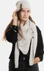 A woman wearing a beige knit hat and scarf. Produktbild-Vorschau