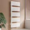 A white designer radiator in a bathroom setting, next to a large potted plant and a shower enclosure. Podgląd zdjęcia produktu