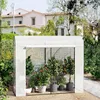A white greenhouse with plants inside, set in a garden with a house in the background. Náhľad obrázku produktu