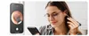 A woman is using an ear cleaning device while looking at her phone, which displays a live feed from the device. Produktbild-Vorschau