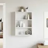 A white wall-mounted shelf with decorative items. Produktbild-Vorschau