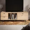 A modern wooden TV stand with drawers and shelves, holding books and a game console, in a living room setting. Produktbild-Vorschau