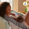 A mother is breastfeeding her baby while sitting on a couch. Náhled obrázku produktu