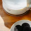 A close-up of a kettle and cookies on a wooden table. Produktbild-Vorschau
