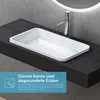 A white rectangular sink with a thin rim and rounded corners is placed on a dark wooden countertop. A chrome faucet is visible behind the sink. A circular illuminated mirror is in the background. Anteprima dell’immagine prodotto