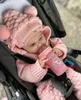 A baby in a stroller is drinking from a pink baby bottle. Podgląd zdjęcia produktu