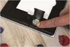 A finger presses down on the battery compartment of a kitchen scale, with berries scattered on a wooden surface. Anteprima dell’immagine prodotto