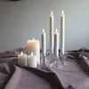 A collection of white LED candles of varying heights are arranged on a draped purple fabric. Podgląd zdjęcia produktu