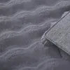 A close-up view of a gray fluffy rug with a wavy texture, showing the underside of the rug in the corner. Produktbild-Vorschau