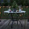 A small decorated Christmas tree with lights on a table on a deck at dusk. Produktbild-Vorschau
