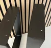 Two black metal table legs are shown in close-up against a slatted wooden background. Náhľad obrázku produktu