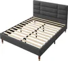 A gray upholstered bed frame with wooden legs and a slatted mattress support is shown from a diagonal angle against a white background. Náhled obrázku produktu