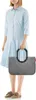 A woman is standing and holding a shopping bag. Podgląd zdjęcia produktu