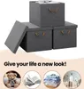 A marketing image showing three grey storage boxes with brown handles, one with its lid open, and below that, four circular images depicting a teddy bear, an open book, folded clothes, and toiletries, with the text 'Give your life a new look!' above them. Produktbild-Vorschau