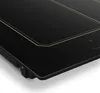 A close-up, angled view of a black induction cooktop with gold trim. Produktbild-Vorschau