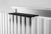 A close-up shot of a black shelf placed on top of a white radiator. Produktbild-Vorschau