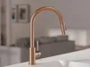 A close-up shot of a copper kitchen faucet on a white countertop, with a blurred background of a living room. Produktbild-Vorschau