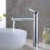 A modern chrome faucet with water flowing into a white basin, set against a textured gray tiled wall. Podgląd zdjęcia produktu