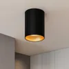 A black cylinder-shaped ceiling light with a gold interior is mounted on a white ceiling. Náhľad obrázku produktu