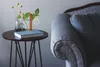 A small round table with a book and plant vases next to a blue upholstered chair. Anteprima dell’immagine prodotto