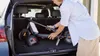 A person is placing a folded electric scooter into the trunk of a car. Produktbild-Vorschau