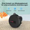 A black portable speaker with a red digital display is shown on a woven mat, with flowers and towels in the background. Text overlays describe playback modes. Produktbild-Vorschau