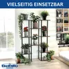 A multi-tiered plant stand filled with various potted plants is displayed in a well-lit room with a window and a bed in the background. Podgląd zdjęcia produktu