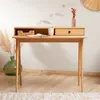 A wooden desk with a drawer and an open compartment, set against a white wall with decorative elements. Produktbild-Vorschau