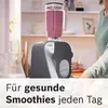 A kitchen scene with a blender filled with a pink smoothie, and a person partially visible on the right. Produktbild-Vorschau