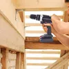 A person is using a cordless drill to attach a metal bracket to a wooden beam. Produktbild-Vorschau