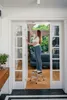 A woman is using a step stool to reach something high up in a doorway. Produktbild-Vorschau