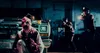 A terrifying clown covered in blood is crouched in front of a truck, while two police officers aim their guns at him. Produktbild-Vorschau