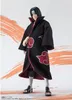 A figure of Itachi Uchiha from Naruto wearing his Akatsuki robe, standing against a backdrop with orange brush strokes. Produktbild-Vorschau