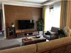 Wohnzimmerwand mit braunen Holzmaserungsplatten hinter einem Fernseher und TV-Ständer Náhľad obrázku produktu