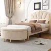 A bedroom scene featuring a bed and a storage ottoman. Produktbild-Vorschau