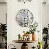 A large Roman numeral wall clock is displayed on a white wall above a wooden table with decorative items. Anteprima dell’immagine prodotto