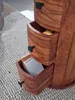 Close-up of a wooden cabinet with three drawers, one of which is open, revealing a notebook. Podgląd zdjęcia produktu