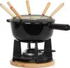 A black cast iron fondue set with wooden-handled fondue forks sits on a wooden base above a burner. Podgląd zdjęcia produktu