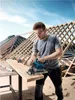 A man is using a cordless circular saw to cut a piece of wood on a construction site, with roof trusses in the background. Anteprima dell’immagine prodotto