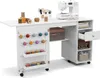 A white sewing cabinet with a sewing machine on top and various sewing supplies stored inside and on the cabinet. Voir les images du produit