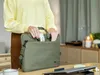 A person is placing a wireless mouse into a laptop bag. Produktbild-Vorschau