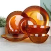 A collection of amber glass tableware, including plates and bowls, arranged on a light-colored surface. Produktbild-Vorschau