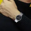 A close-up shot of a person's wrist wearing a silver watch with a black face. Produktbild-Vorschau